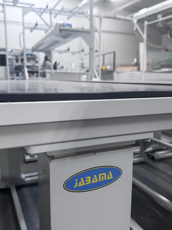 JABAMA lifting column beneath the frame of an electrically height-adjustable workbench